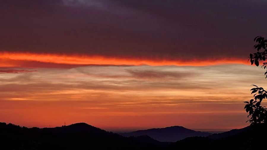 A dramatic sunset unfolds with dark, ominous clouds juxtaposed against a vibrant orange sky, creating a captivating and dynamic scene, possibly a view from the resort