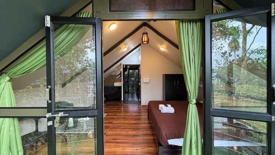 Glass-walled entrance foyer with wooden deck and forest views at Holistic Eco-Resort, Kannur.