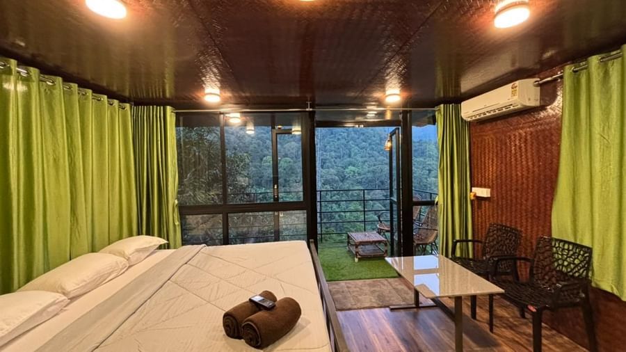 Spacious bedroom with wooden floors and green curtains at Holistic Eco-Resort, Kannur