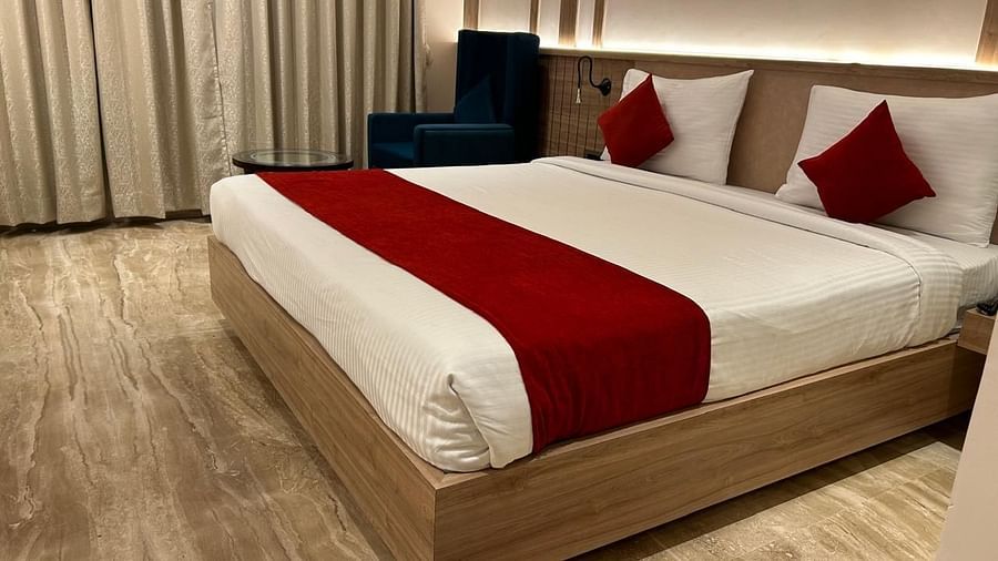  Cosy double room at Hotel City Inn, Varanasi, featuring wood flooring, a plush red-accented bed, and a welcoming ambiance.