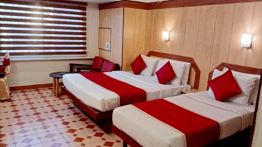 Room with a single bed, a double bed, and a seating area at Hotel Swagath, Bangalore