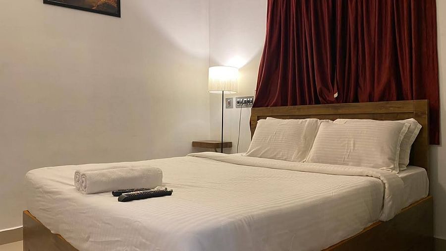 A side view of a bed with bedding in a room with a wall frame and bed lamp