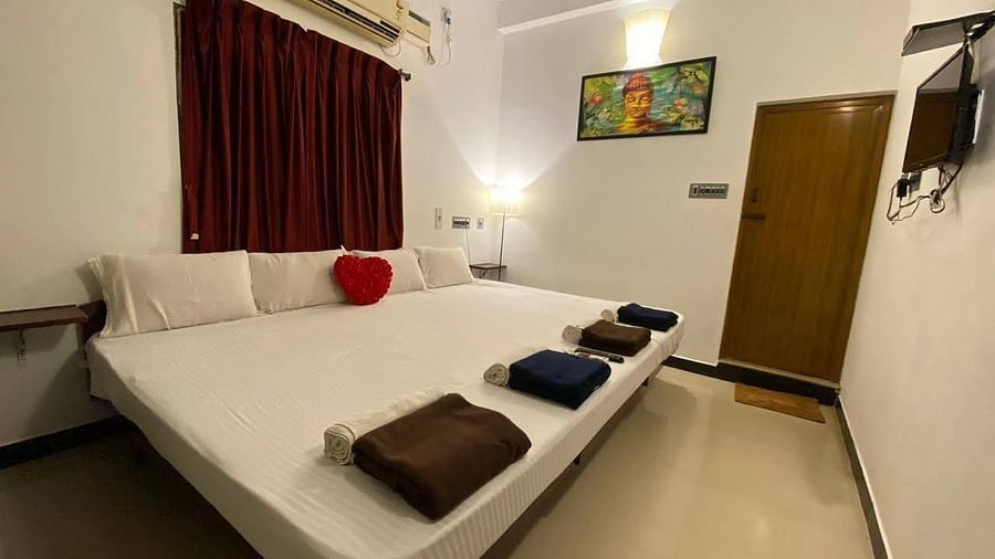 A full view of bedroom with a bed with bedding, split AC and a wall frame | La Paradise Residency, Pondicherry