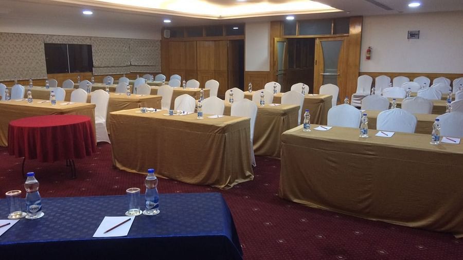 A banquet hall with seats arranged in a classroom set up, with a water bottle and a notepad for every seat present - Monarch Hotels