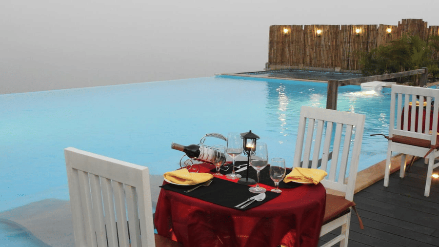 Dining table by the poolside which has wine bottles and glasses placed - Polo Cherrapunjee Resort