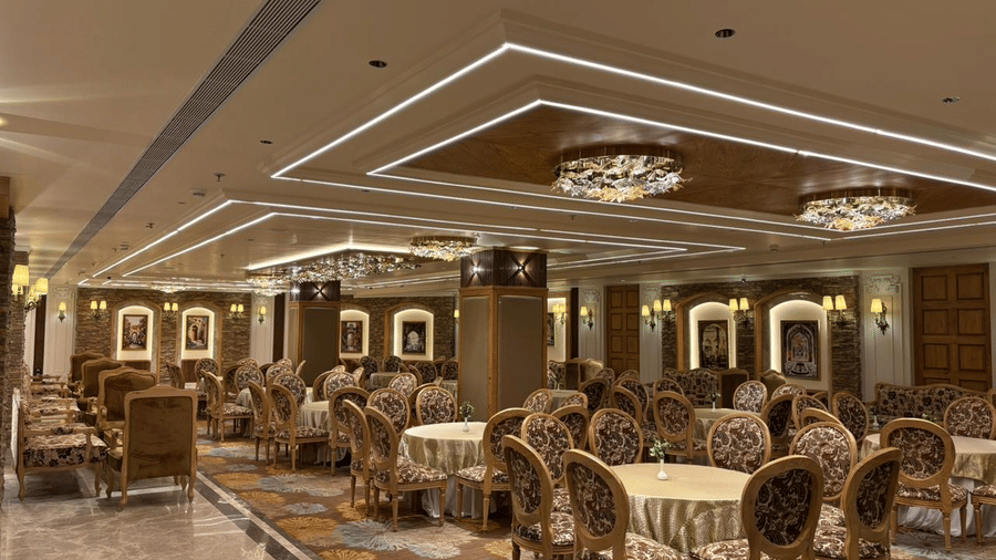 Banquet hall at Presidium Sarovar Premiere, Dalhousie with round dining tables and elegant ceiling lights.