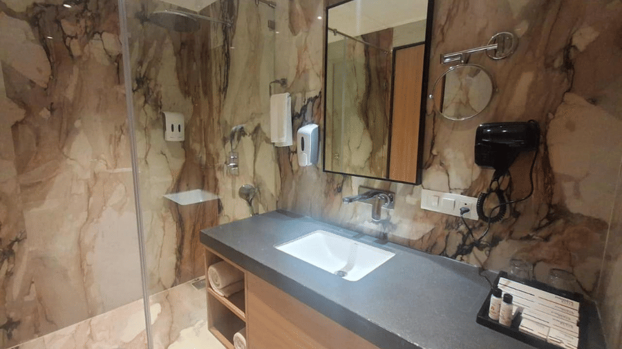 This sleek washroom includes a dark countertop sink and glass shower cabin - Pride Elite Himmatnagar, Gujarat