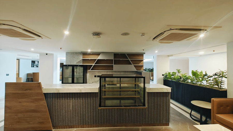 Front view of the Mr. Confectioner bakery counter at Pride Premier Greater Noida, featuring wood panelling and glass display cases in the lobby.