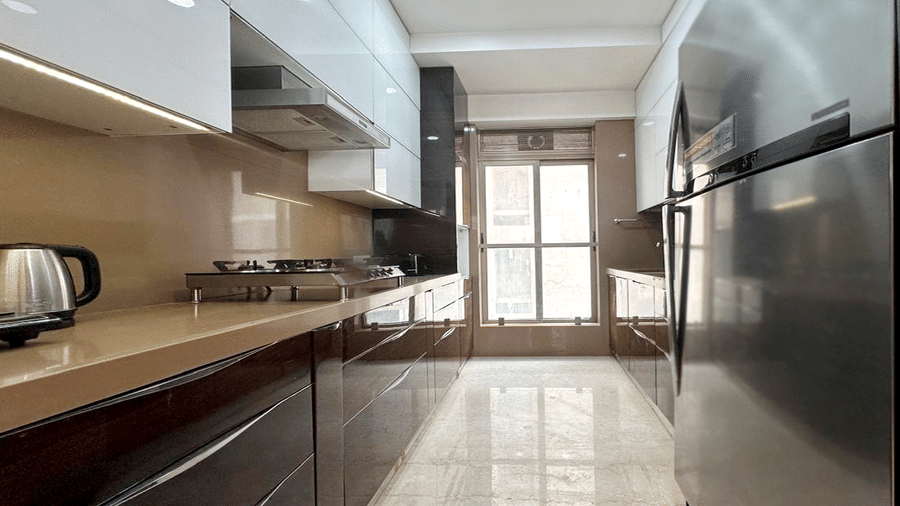 Fully equipped modular kitchen at Theory9 - Premium Serviced Apts, Khar, with sleek brown cabinets and stainless steel appliances.