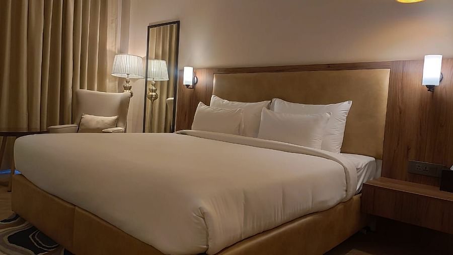 A warm-lit room featuring plush bed with lamps on both sides and a couch in the background