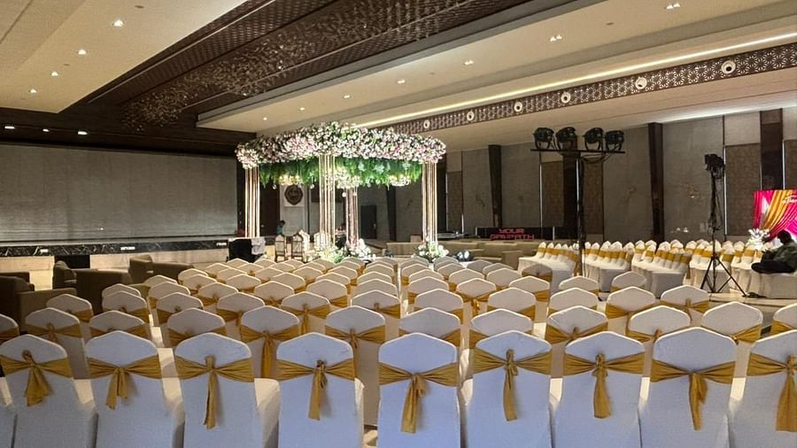 An event hall with rows of covered chairs facing a central stage, lit with decorative lights.