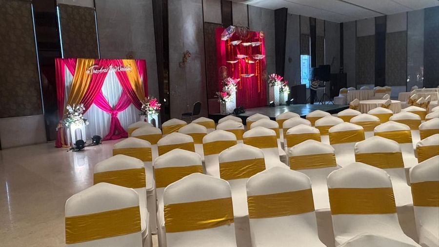 An event hall with rows of covered chairs facing a central stage, lit with decorative lights.