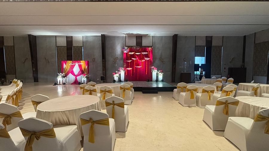A well-lit banquet hall with rows of white chairs 