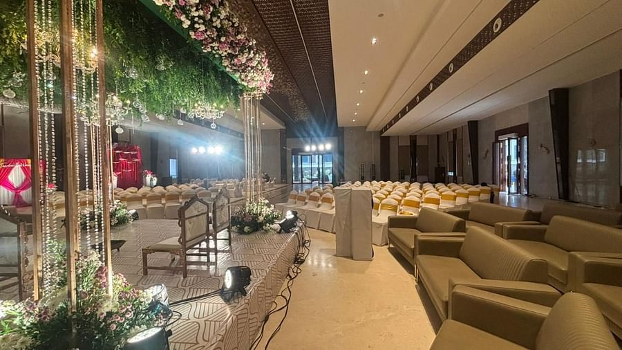 A luxurious indoor event space with elegant sofas, floral decorations, and a well-lit seating arrangement.