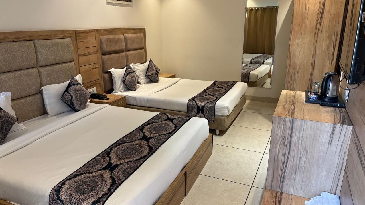 A spacious hotel room with two large beds, a wooden headboard, and minimalist decor.
