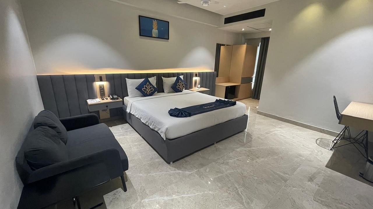 Suite featuring a large bed, cosy seating area, work desk, and modern decor with marble flooring at Hotel Kyzen HiTech City – Your Zenly Stay