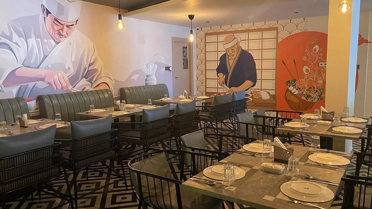 Restaurant seating area featuring artistic wall designs and neatly arranged tables at Hotel Kyzen, Hitech City.