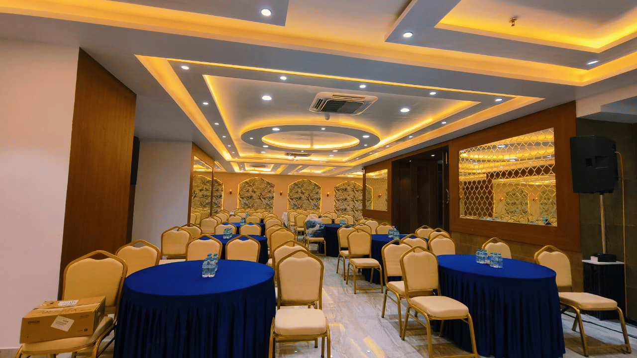 Hotel Mumbai House, Vashi banquet hall with round tables, arranged seating and modern warm-toned lighting.