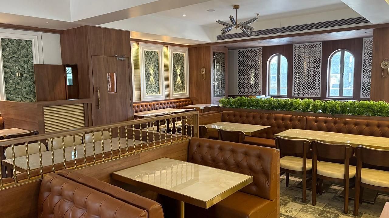 A warmly lit dining area with booth seating and wooden tables - Melior Inn