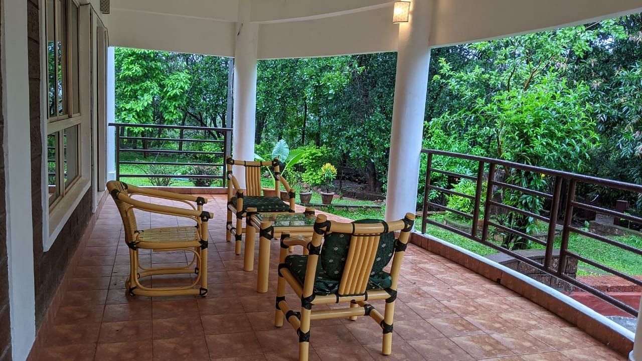 An outdoor seating area with ratan chairs and view of the surrounding greenery at The Conservancy Bungalow.