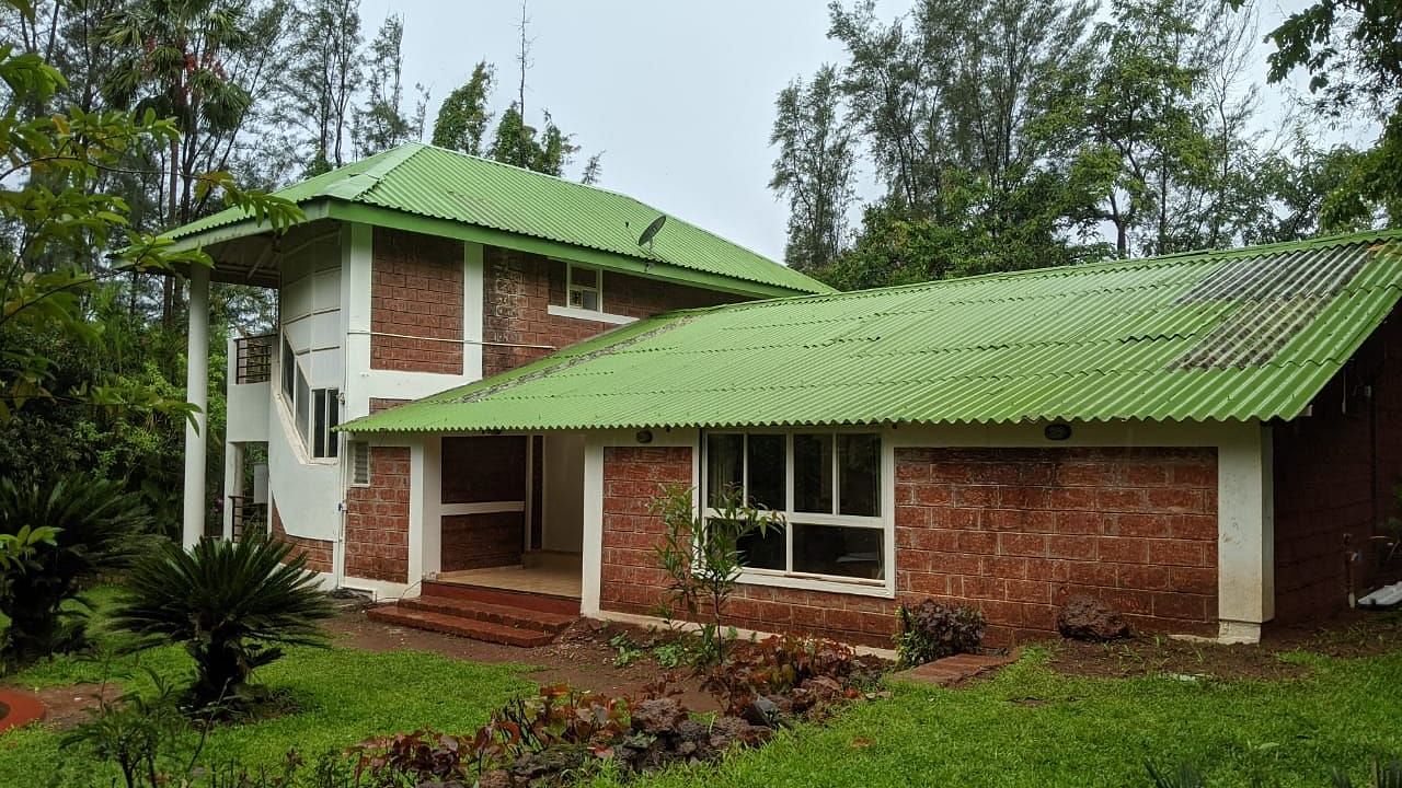 The Conservancy Bungalow with a green roof, surrounded by lush greenery and trees.