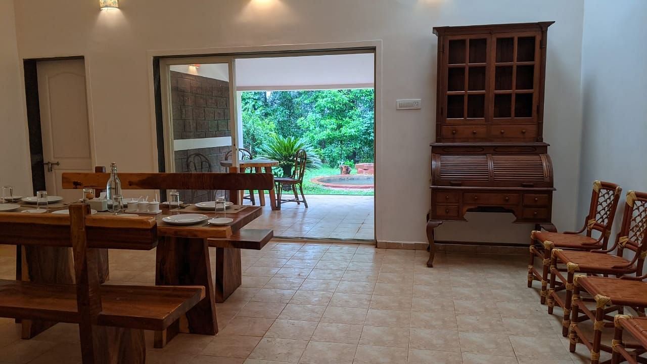 Dining area with wooden furniture and an open view of greenery at The Conservancy Bungalow.