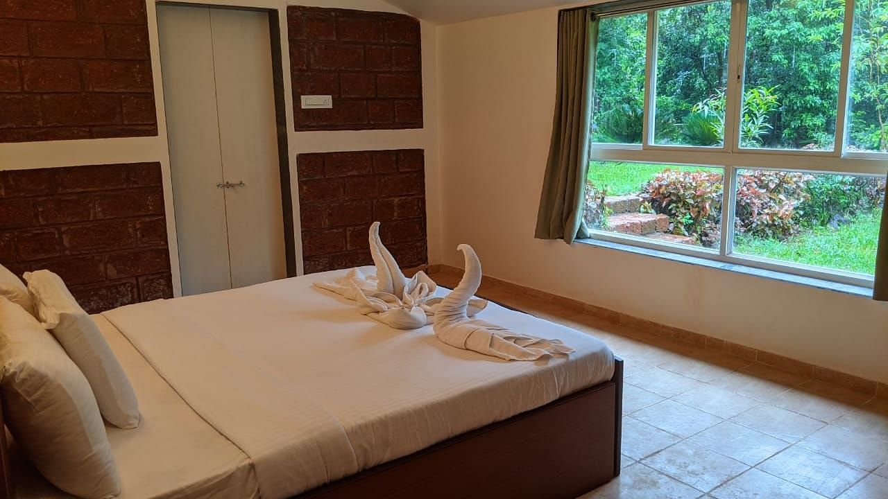 A well-lit bedroom with a large bed, window, and neatly folded towels at The Conservancy Bungalow.