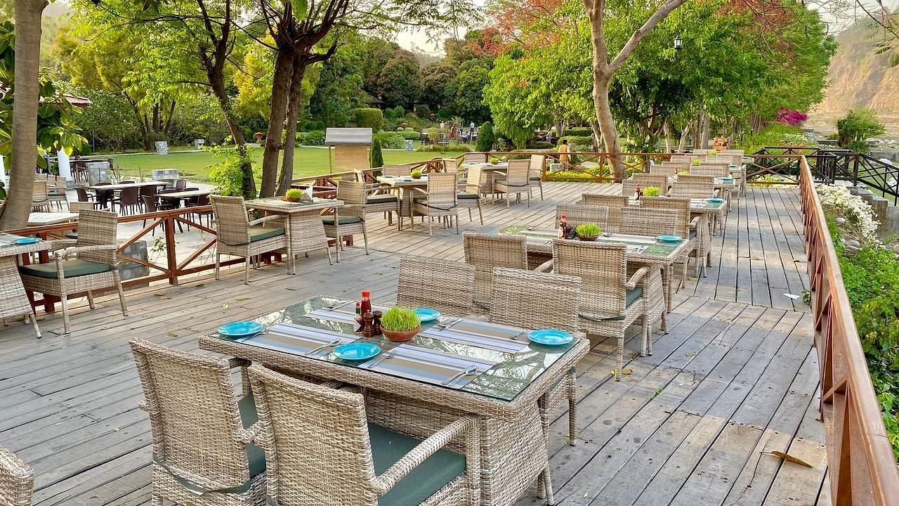 An image of outdoor seating area with wooden chairs and table surrounded by plants and trees - The Riverview Retreat, Corbett