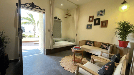 Indoor seating area with sofa, table, open doorway and wall art at Beelwa Palace, Jaipur