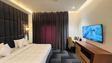 full view image of the executive room with a plush double bed and a wall mounted television at Eminence The Corbett