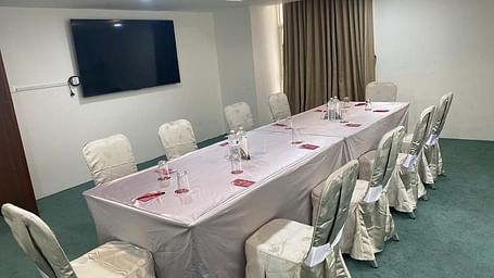 A table set for 10 with chairs, a window with curtains and TV