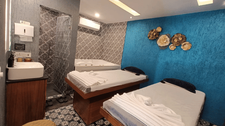 Interior of a peaceful wellness spa room featuring two massage beds and blue walls.