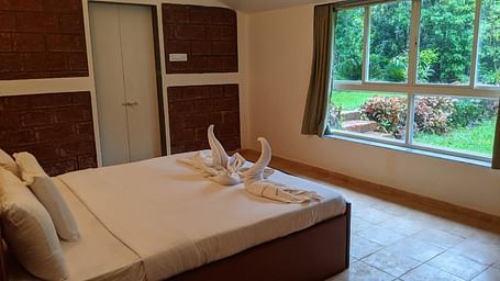 A well-lit bedroom with a large bed, window, and neatly folded towels at The Conservancy Bungalow.