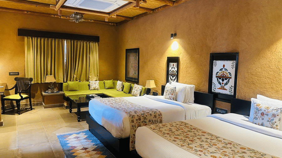 A suite featuring a comfortable bedroom and an adjoining living area at Aamaghati Wildlife Resort.