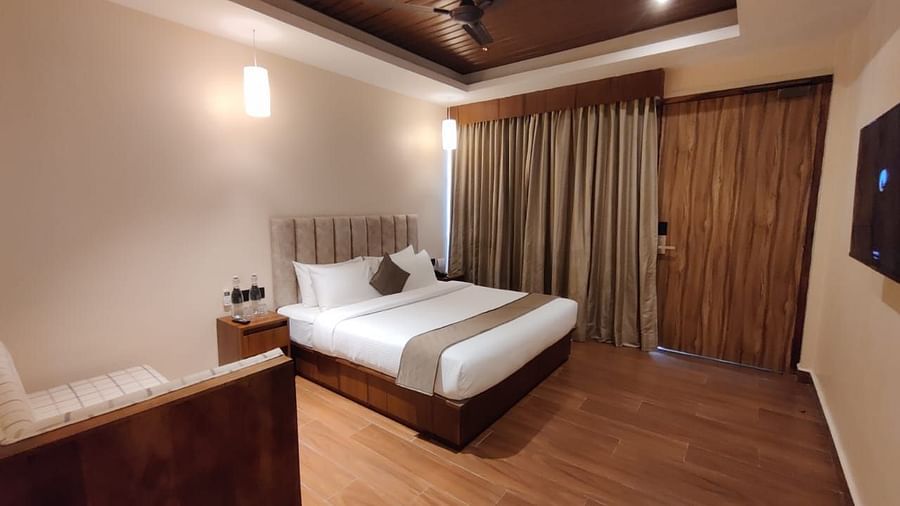 Elegant bedroom with modern wooden furniture, a king-sized bed, and soft drapes - Arina Island Resort, Swaraj Dweep