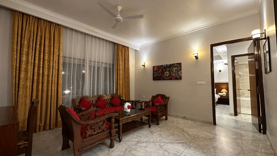 A bedroom featuring a seating area, bed, and open doorway at AS Hotels, Khajuraho