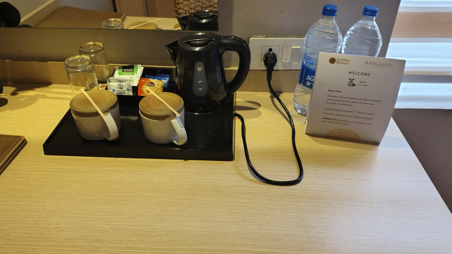 Tea and coffee maker at Lawn View Room at Cholaa Dynasty, Kumbakonam. It also features two cups with lids and mineral water bottles.