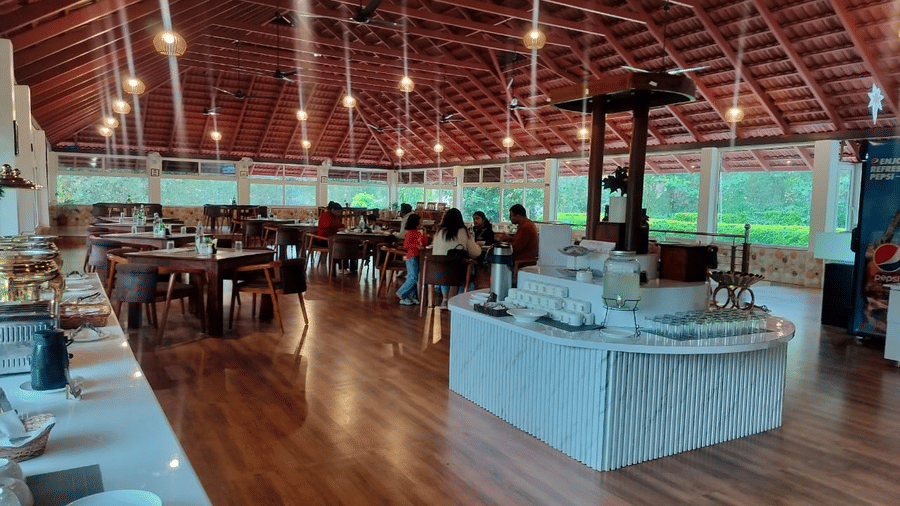 restaurant wooden beam ceiling, warm lighting, wooden floors, and a buffet station at Coorg Orange Blossom Resort & Spa