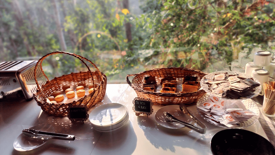 buffet table setting next to a window with two woven baskets containing food at Coorg Orange Blossom Resort & Spa