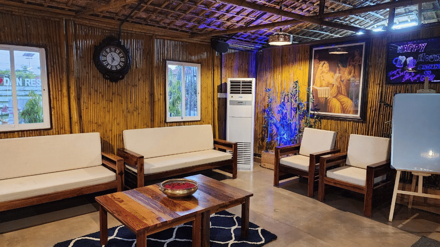 Cosy indoor waiting area with wooden sofas, a coffee table, and traditional decor - DAN Resorts & Weddings, Palghar