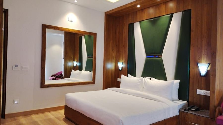 A large bed placed next to a mirror  in Premium Room With Balcony at DLS Ark Holiday Inn, Banikhet.