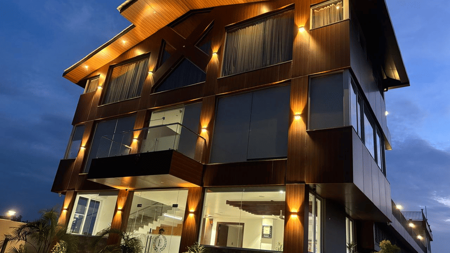 Close up of the facade of Eminence The Corbett resort in Ramnagar, with exterior lighting and beautiful evening sky in the background.