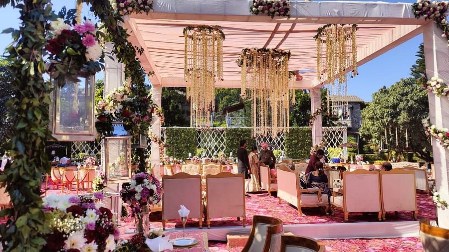 An outdoor wedding ceremony setup with a decorated stage, floral arrangements, and seating for guests.