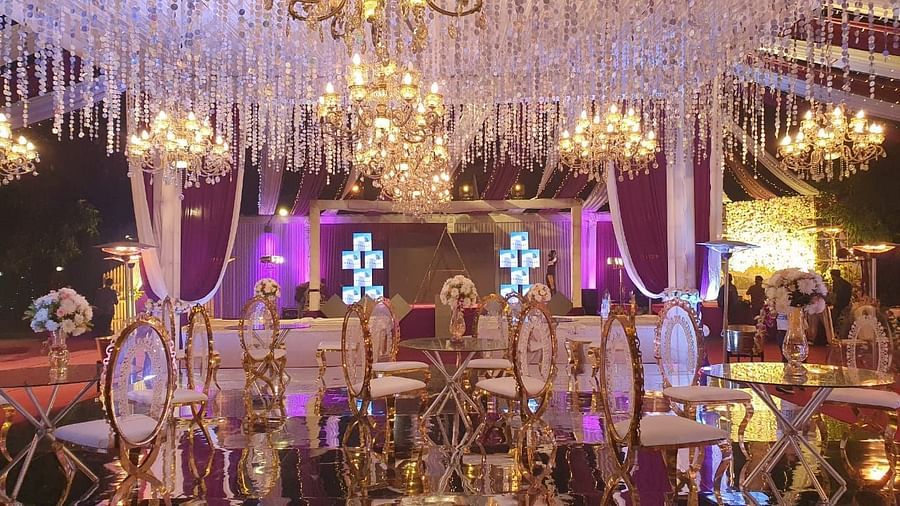A lavishly decorated wedding hall with chandeliers, draped fabric, and tables set for guests.