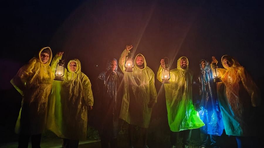 A group posing wearing raincoats and holding lanterns in the dark - Evergreen County