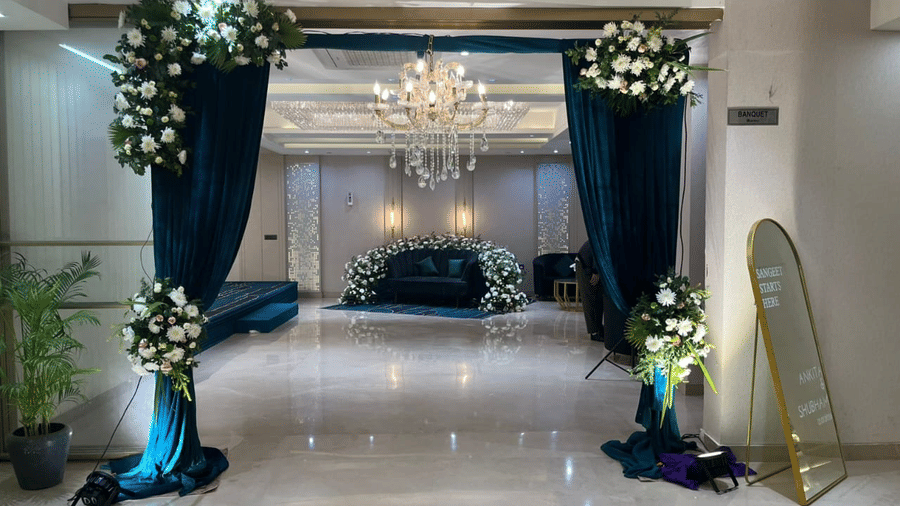 A beautifully decorated entrance of the Crystal Hall at Hotel 91 Privé, Gurugram, decorated with dark blue drapes and floral arrangements.