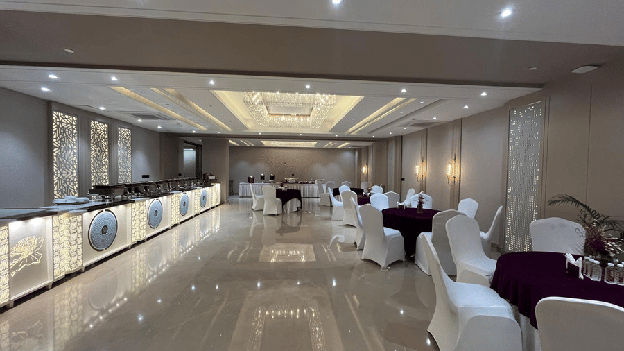 The empty walking space at the Sapphire Hall featuring a buffet counter and tables and chairs arranged at the other end at Hotel 91 Privé, Gurugram.