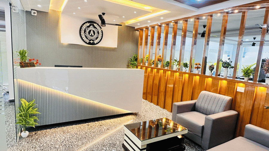 Hotel reception desk with a logo on the wall and a seating area with a sofa and armchair | Hotel Aurora Bliss