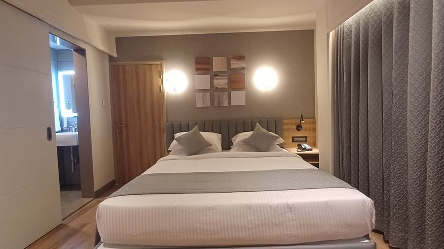 Image of a room wuth double bed and a door on the side of the bed at Hotel Raai, Hosur.