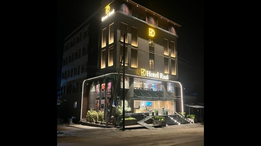 Facade of Hotel Raai at night featuring multiple storeys,  and each room is illuminated with lights. The brand name is illuminated as well.